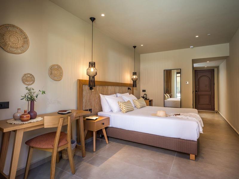 Helles Schlafzimmer mit Doppelbett, Holzmöbeln, Korbdekor an der Wand und modernem Lampenlicht.