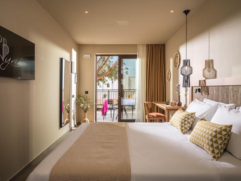 Helles, modernes Hotelzimmer mit großem Bett, Balkon, Schreibtisch und neutralen Farben.