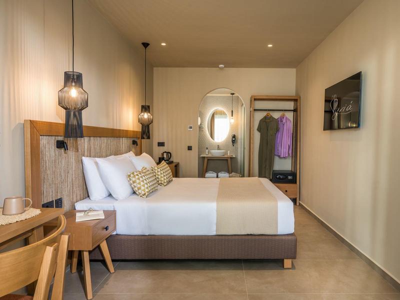 Modern eingerichtetes Hotelzimmer mit Doppelbett, Holzmöbeln und weichem warmem Licht.