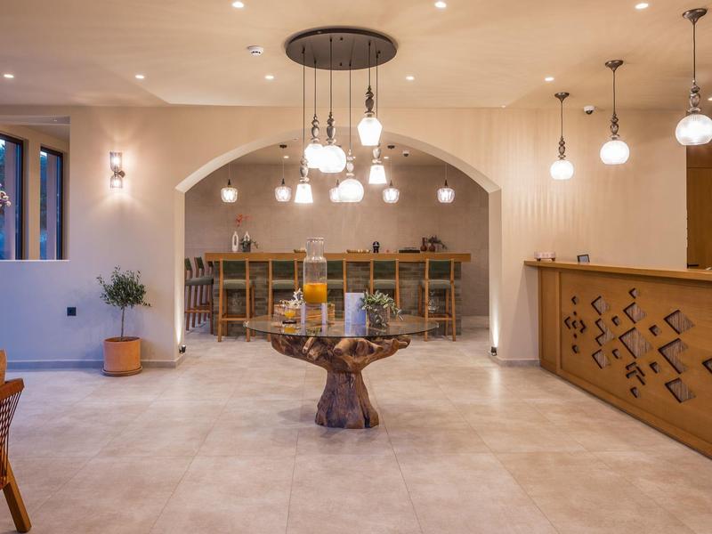 Großer Raum mit hellen Wänden, Baumstamm-Tisch in der Mitte, Bücherregal und Theke rechts.