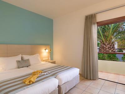 Modernes Schlafzimmer mit hellblauen und weißen Wänden, zwei Betten, Fenster und Tür zum Balkon.