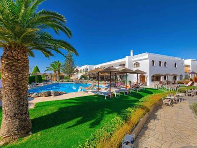 Ein Hotel mit Pool, Palmen und Liegestühlen unter klarem blauem Himmel.