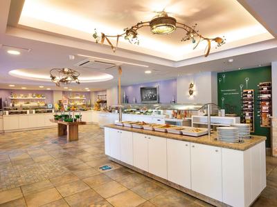 Großer heller Buffetraum mit warmen Holz- und weißen Möbeln sowie modernen Deckenleuchten.