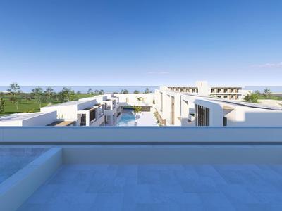 Uitzicht vanaf een dakzwembad op moderne witte gebouwen en groen land onder een heldere lucht.