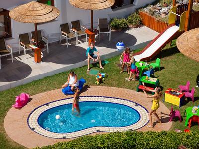 Kinderen spelen in een hotelzwembad met glijbanen en kleurrijke stoelen.