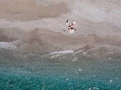 Playa vacía con agua turquesa y dos personas caminando de la mano.