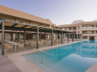Piscina moderna de hotel con áreas cubiertas para sentarse y agua clara y reflectante al aire libre.