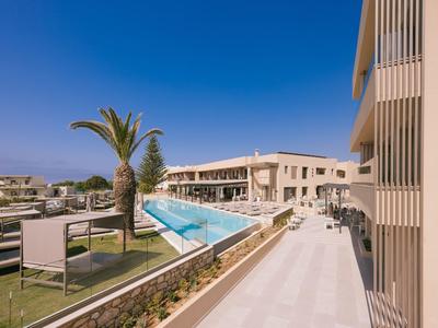 Complejo hotelero moderno con piscina, sillas de descanso y arquitectura mediterránea bajo cielo despejado.