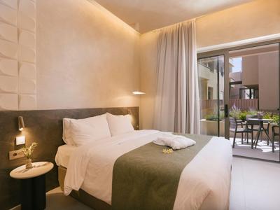 Habitación acogedora con cama grande, luz suave y acceso a balcón con zona de estar.