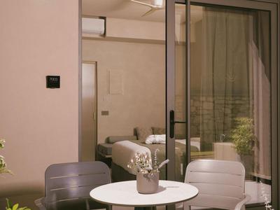 Área exterior moderna con mesa redonda y tres sillas frente a una puerta de vidrio.