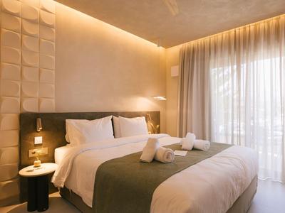 Habitación de hotel moderna con cama grande, iluminación suave y ventanas grandes.