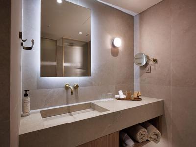 Baño moderno de hotel con espejo iluminado, lavabo y toallas suaves.