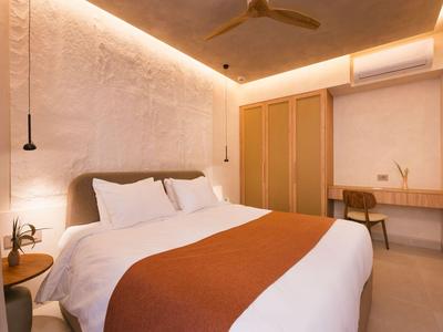 Habitación de hotel moderna con cama grande, cubrecama naranja y espacio de trabajo sencillo.