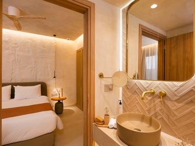 Área de baño moderna en hotel con lavabo y dormitorio adyacente.