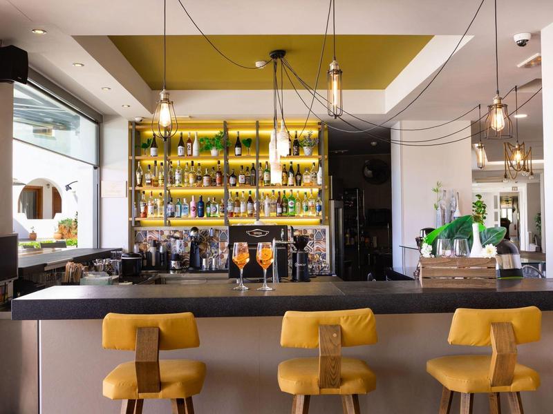 Moderne bar met gele krukken en verlichte planken vol flessen.