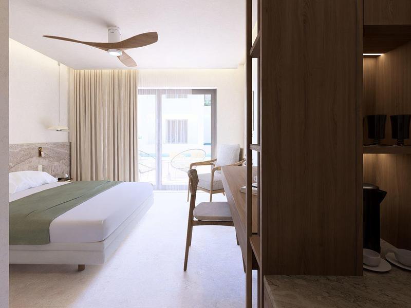 Moderne hotelkamer met bed, stoel, plafondventilator en daglicht door raam.