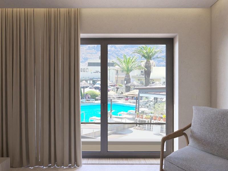 Uitzicht vanuit de hotelkamer op een zwembad met parasols en palmbomen.