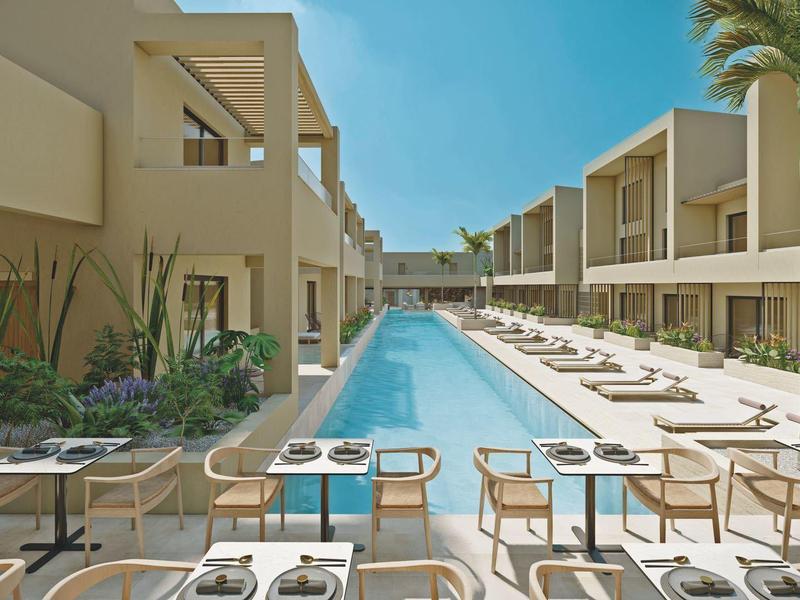 Modern hotelzwembad met ligstoelen en tafels in een zonnige omgeving.