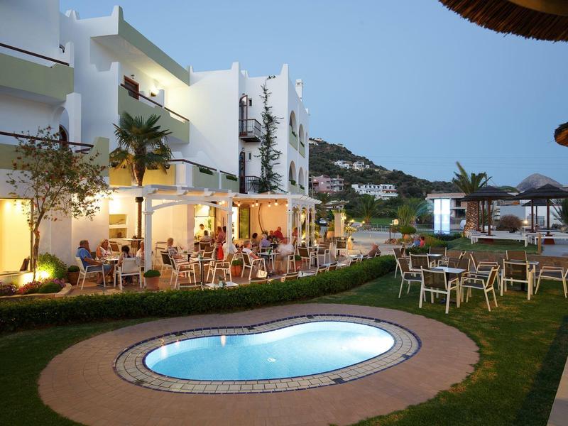 Verlichte zwembadomgeving met buitenbar en zitplaatsen voor een hotel 's nachts.