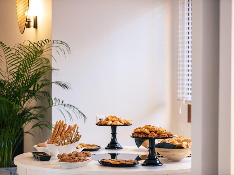 Verschiedene Gebäcksorten sind auf schwarzen Tortenständern auf einem weißen Tisch dekorativ angerichtet.