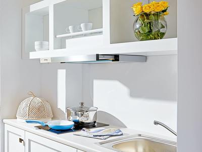 Moderne hotelkeuken met witte kast, fornuis, afzuigkap en gele rozendecoratie.