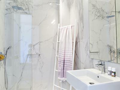 Moderne badkamer met marmeren tegels, wastafel en douche in een hotel.