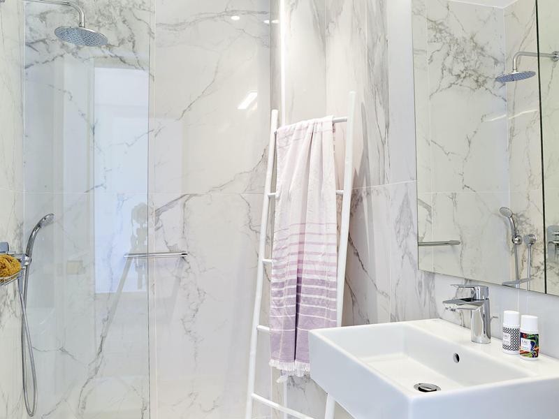 Moderne badkamer met marmeren tegels, wastafel en douche in een hotel.