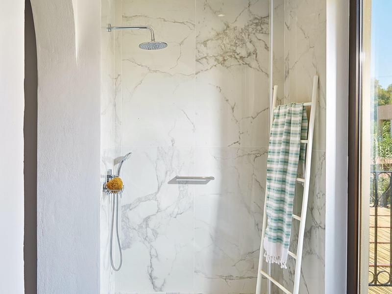 Moderne douche met regendouchekop, handdouche en groen geruite handdoek aan de muur.