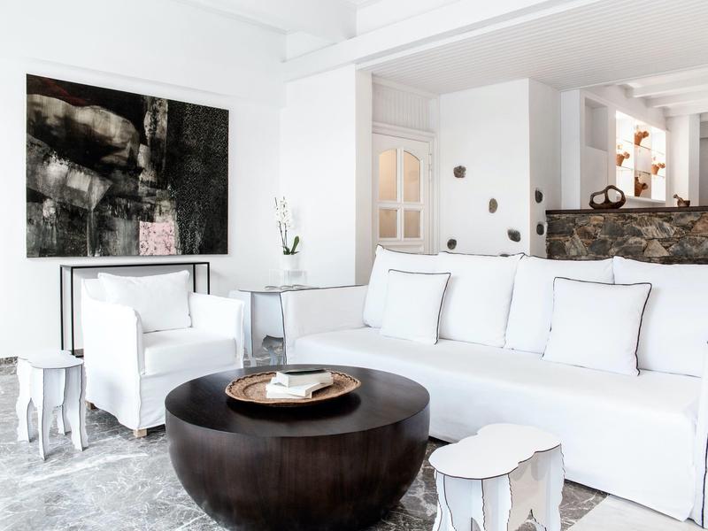 Lichte woonkamer met wit meubilair, zwarte salontafel en moderne kunst aan de muur.