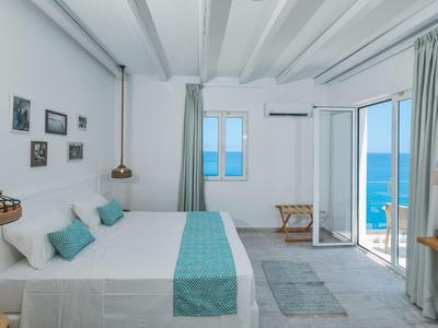 Camera d'albergo luminosa con letto matrimoniale e balcone vista mare alla luce del giorno