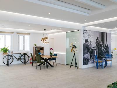 Lounge dell'hotel luminosa e moderna con biciclette nere, tavoli di legno e grande parete fotografica in bianco e nero.