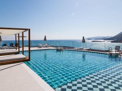 Piscina moderna con lettini e vista sul mare in una giornata di sole.