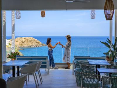 Due donne brindano su una terrazza con vista mare.