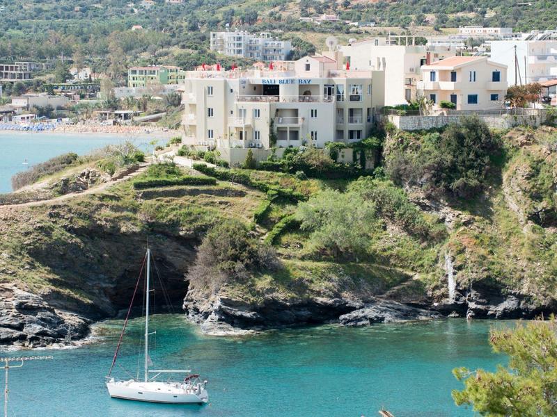 Barca a vela su acque calme vicino a scogliere con edifici sullo sfondo