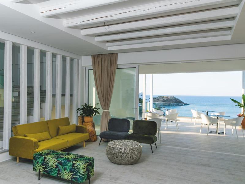 Soggiorno moderno con divano giallo e vista mare attraverso grandi finestre.