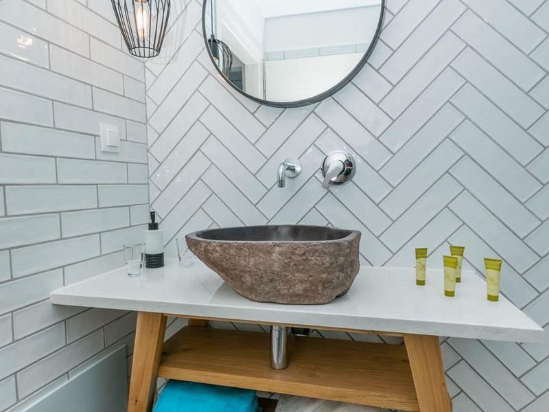Bagno moderno con specchio rotondo, lampada sospesa e mobile in legno con lavabo marrone.