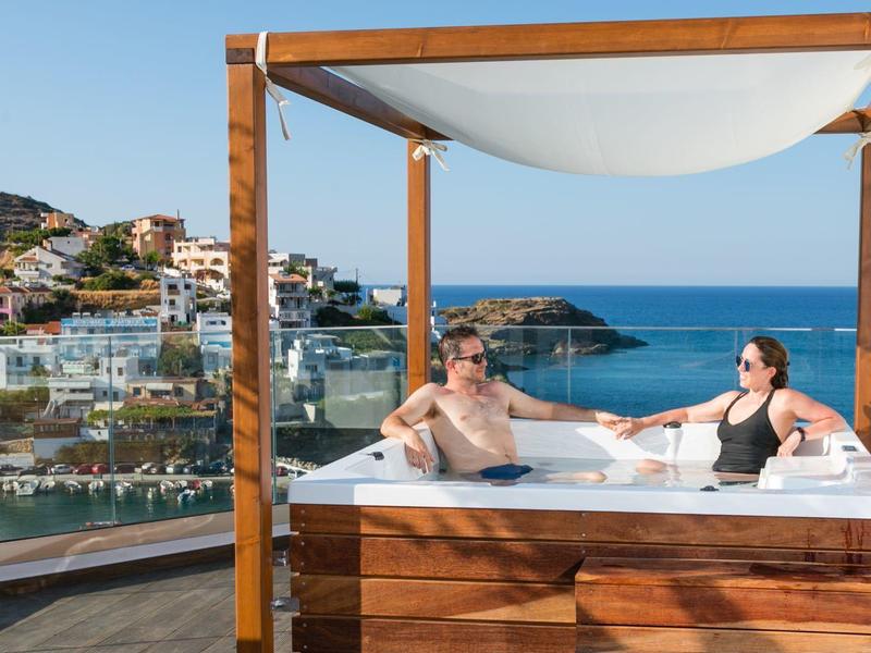 Coppie si rilassano su un letto di legno con vista sul mare e sulla città.