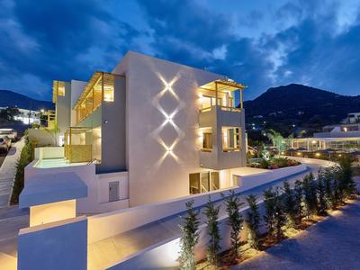 Modern hotelgebouw met verlichting bij schemering en bergachtige achtergrond.