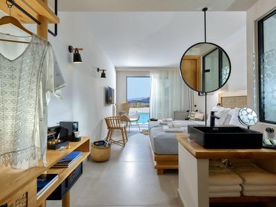 Moderne hotelkamer met bed, spiegel, wastafel en zeezicht.