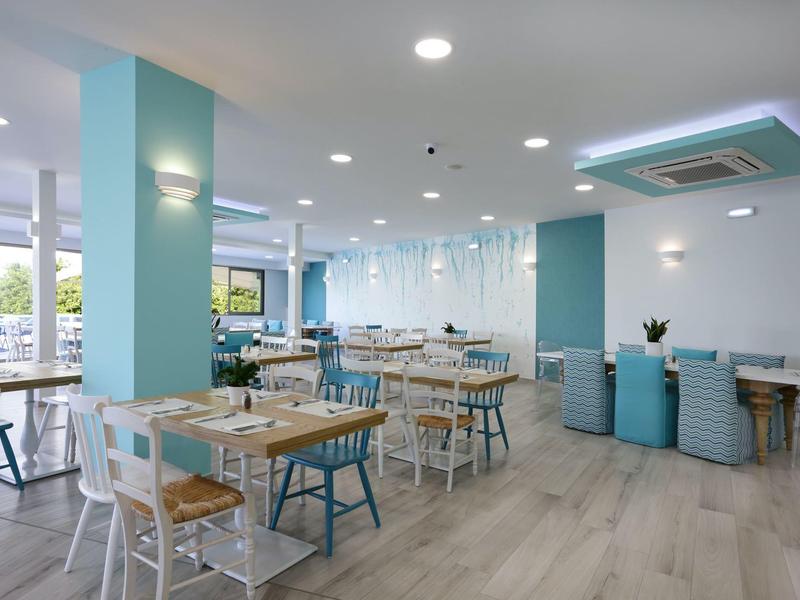 Lichte, moderne ontbijtruimte met blauwe en witte stoelen en houten tafels.