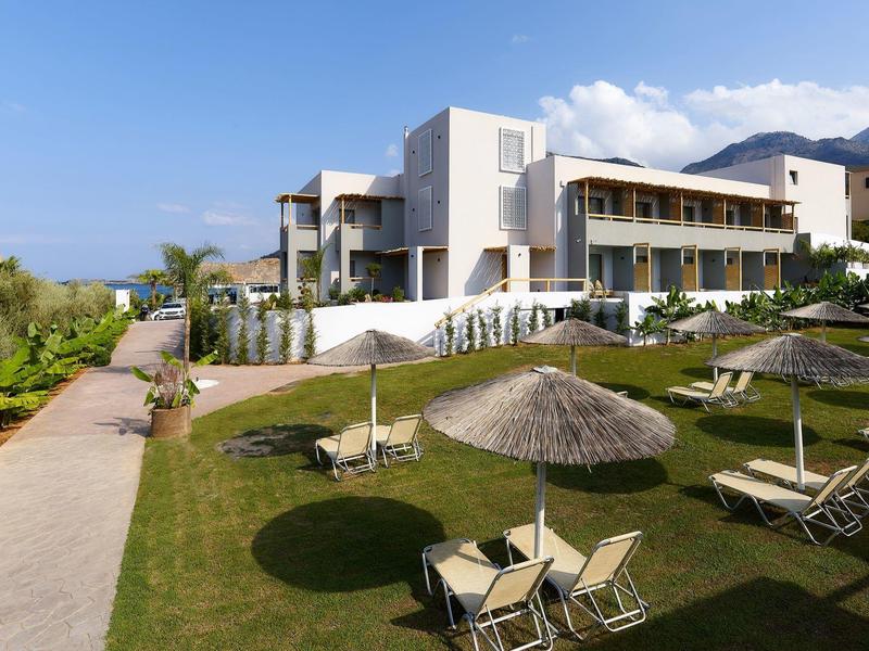 Modern hotelgebouw met ligstoelen en parasols op goed onderhouden gazon