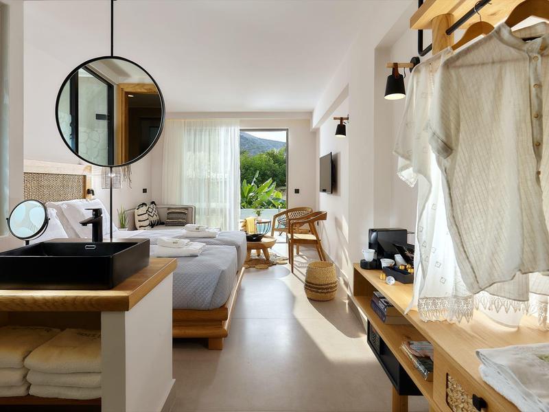 Moderne hotelkamer met tweepersoonsbed, klein bureau, open kledingkast en balkonuitzicht