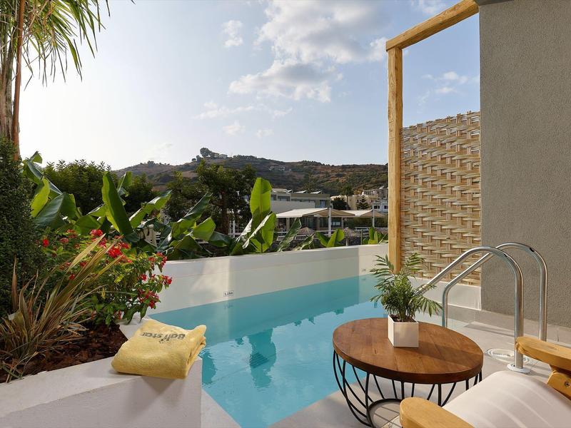 Moderne poolomgeving met tropische planten en uitzicht op bergen bij zonnig weer.