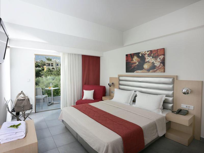 Modern hotelkamer met tweepersoonsbed, balkon en uitzicht op een zwembadgebied.