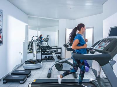 Vrouw rent op een loopband in een lichte, moderne hotelgym.
