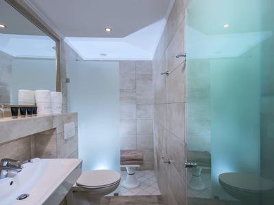 Modernes Badezimmer mit weißem Waschbecken, Toilette und begehbarer Dusche mit Glaswänden.