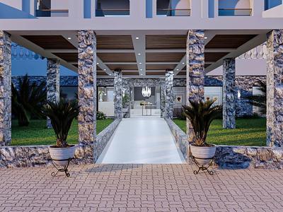 Moderner Eingangsbereich mit Steinverkleideten Säulen, Glaswänden und symmetrischen Pflanzen.