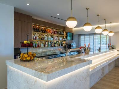 Moderner Hotelbarbereich mit beleuchtetem Marmor-Counter und hängenden Kugelleuchten.