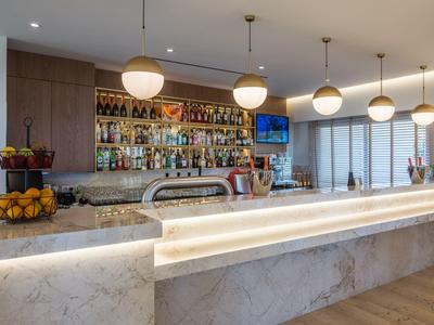 Moderner Hotelbarbereich mit beleuchtetem Marmor-Bar und Wänden mit spirituosenregal.