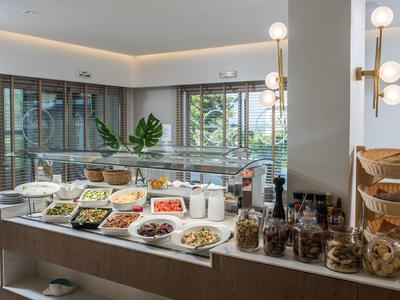 Hell eingerichteter Buffetbereich mit einer Vielzahl von Speisen und Snacks in Gläsern und Schalen.